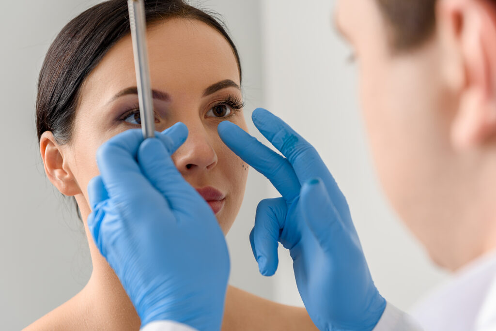 A doctor measuring a woman's nose before a procedure