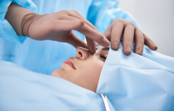 Surgeon adjusting a patient's nose during a rhinoplasty procedure.