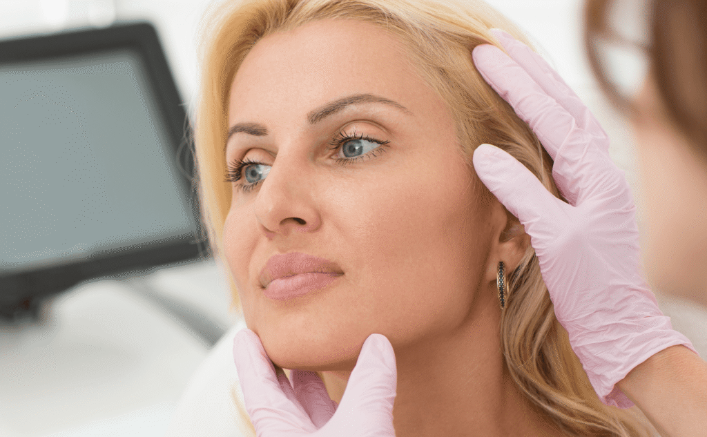 Surgeon examining a patient's jawline and hairline for facelift consultation