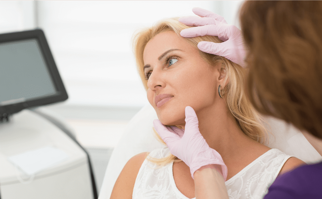 Doctor assessing patient's face and hairline during facelift consultation
