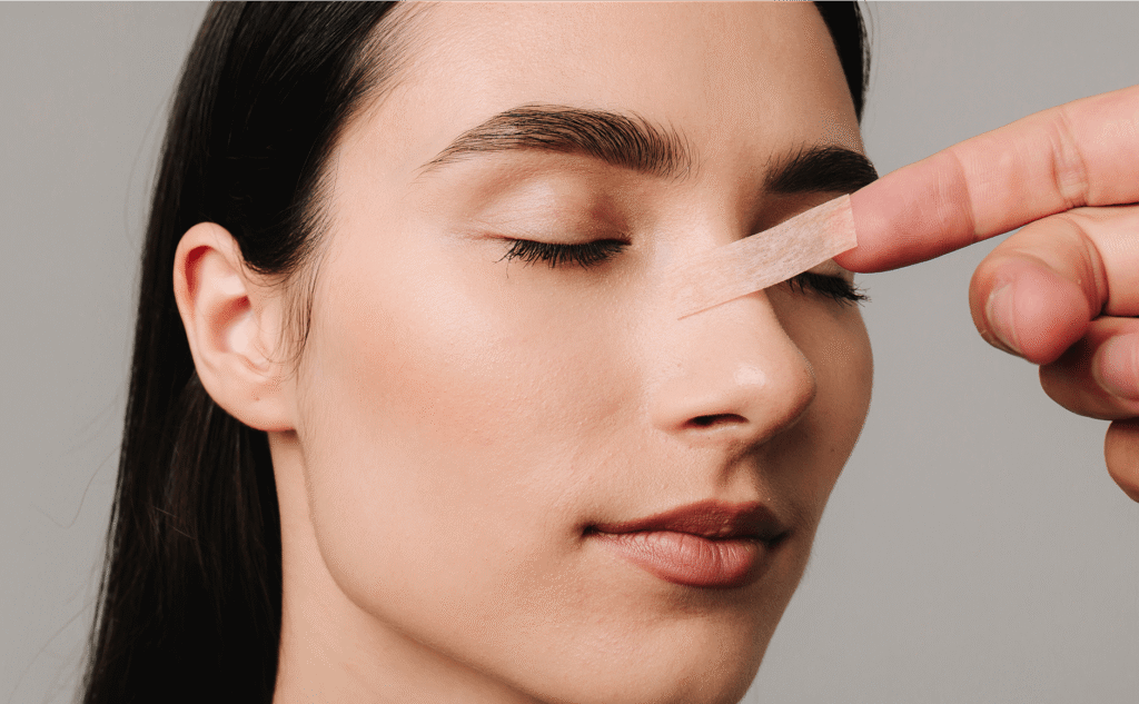 Woman having a small strip of tape applied near her eye and nose